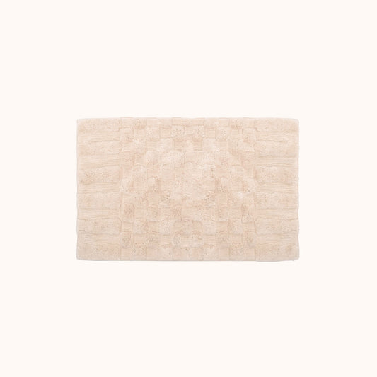 The Clea Bath Mat is a soft, neutral blush hue with a subtle check pattern created by contrasting shag heights. This bath mat is perfect for adding just a hint of color and texture. Ethically produced and hand made in India.