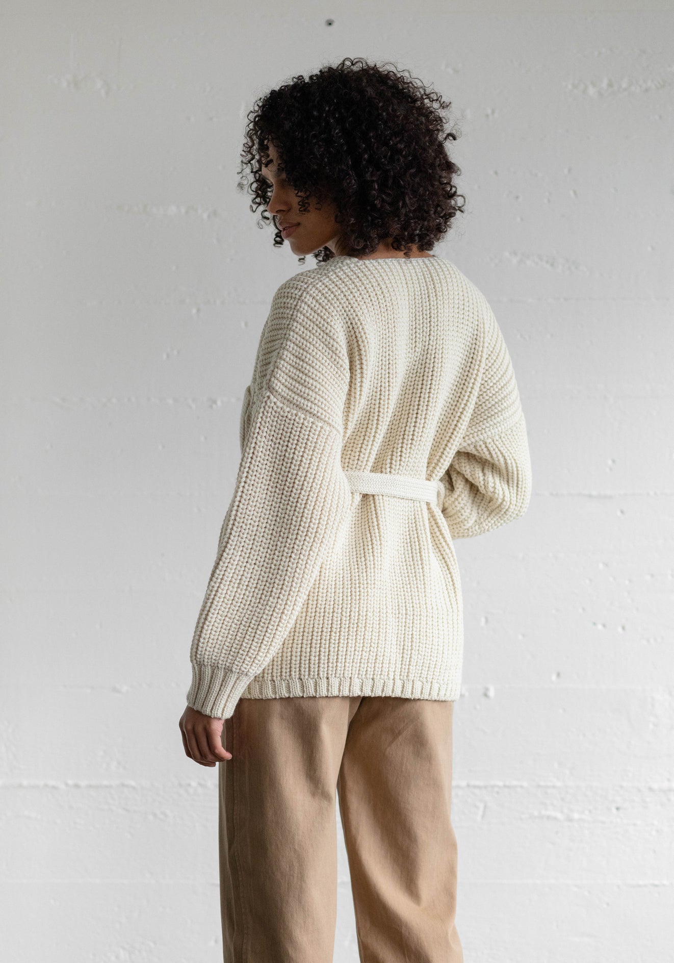 Knit in Peru from 100% undyed Andean Highland Eco Wool. Styled with a wide bulky stitch, front pockets, and an adjustable belt closure to wrap up for cold days ahead.