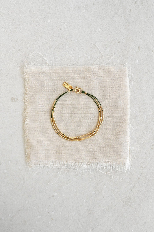 A refined and effortless bracelet designed to elevate your day-to-day. The Ara is a triple-stranded silk cord bracelet stacked with gold tubes and rounds that shift freely.