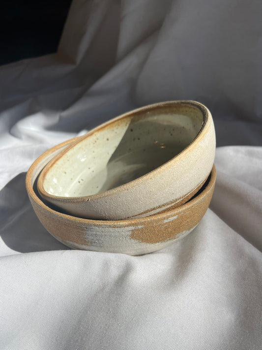 An earthy wide bowl with a raw textured exterior and speckled white interior glaze. Perfect for salads, pastas, whatever you're serving up to eat! Measures 9" across and 1.5" tall. Food safe, hand wash recommended.