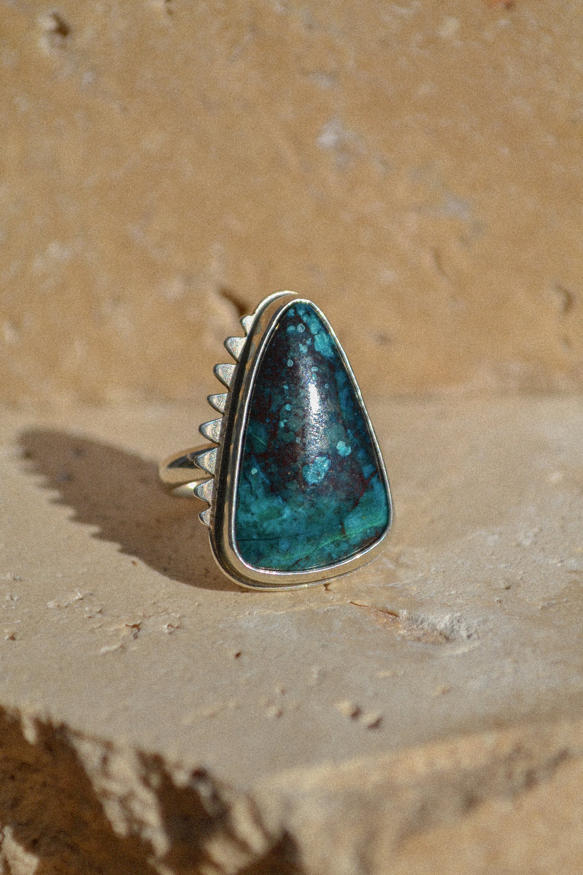 This is a beautiful triangular stone with deep dark blues, greens and reds. The stone is set in a thick bezel with hand cut serrated surround. chrysocolla 925 sterling silver 