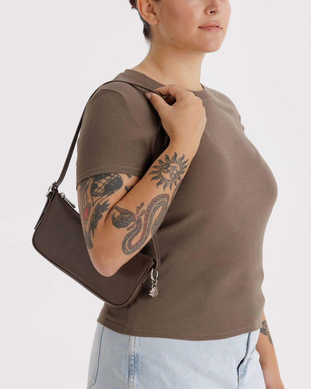 Made from recycled leather, Baggu's sleek Pochette features built-in card slots for organization, a metal smiley face charm, and an adjustable strap.