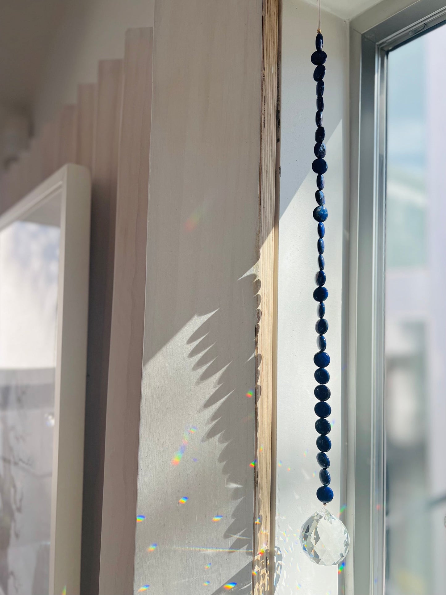 Lapis Lazuli window prism transforms any space into a zen den - hang in a sunny spot & watch the rainbows dance! Disk shaped beads twist when hung, revealing a moon phase pattern ~  Designed in California by Carrie Marill.