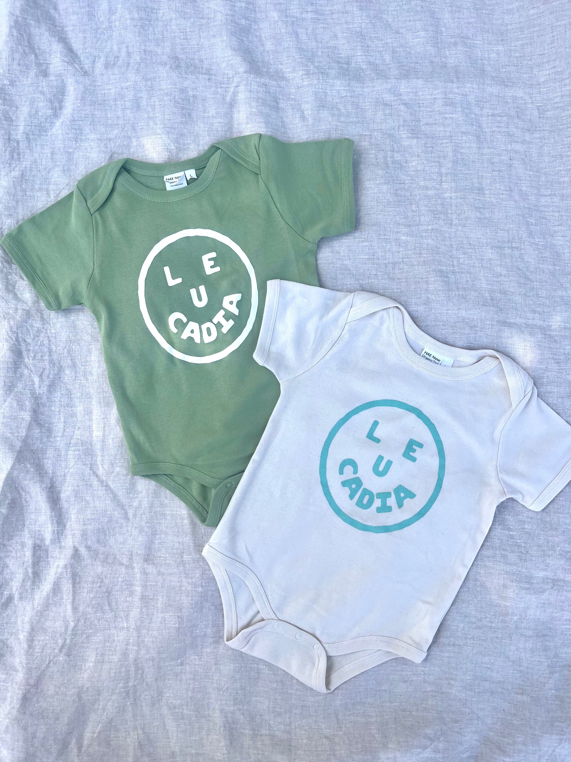 A fun little organic infant onesie with a super cute little Leucadia smiley face by local artist Zach Smith. Printed on an organic cotton, fair trade onesie with all proceeds to San Diego area families facing housing insecurity. Keep it funky, keep it kind, keep it local.