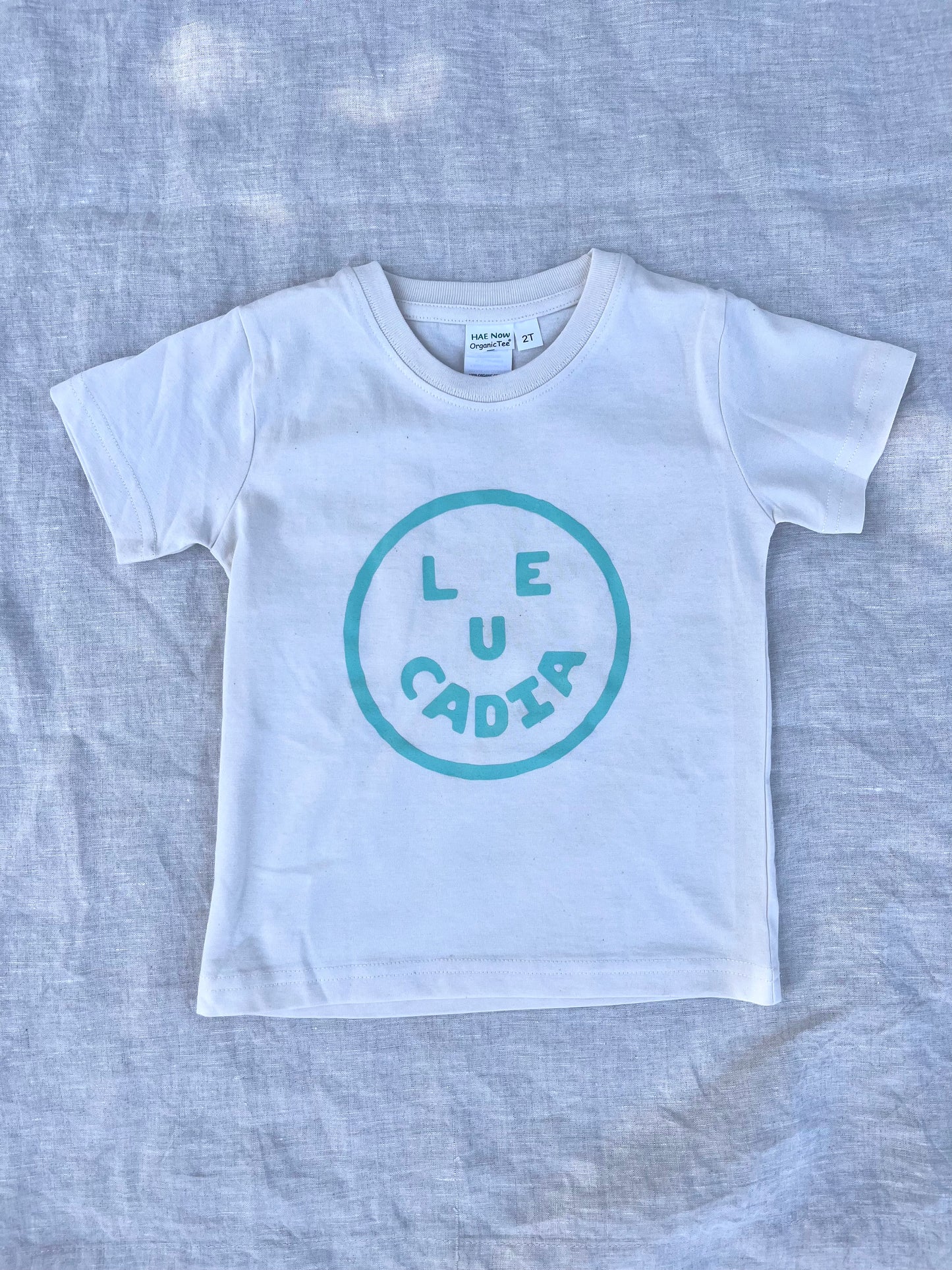 A fun little organic kids tee with a super cute little Leucadia smiley face by local artist Zach Smith. Printed on an organic cotton, fair trade tee with all proceeds to San Diego area families facing housing insecurity. Keep it funky, keep it kind, keep it local.