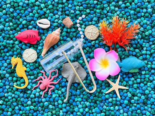 Dive deep for sunken treasure! Includes an assortment of aquatic animals, seashells and plants, with bamboo tongs & cork bottle which provide fine motor tools. Filler is dried chickpea with food color.