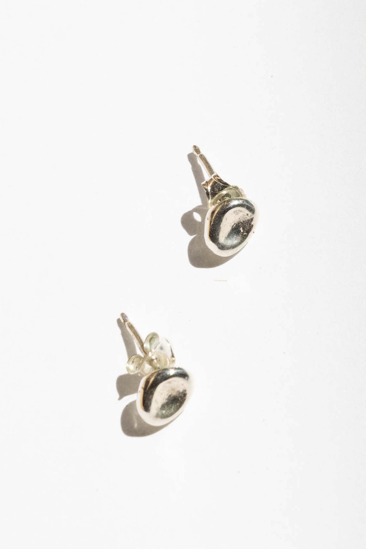 The Puddle stud is inspired by a calm small body of water. Perfect alone or in a second ear piercing.   Hand carved and cast with a high polished mirror finish. Available in solid brass or sterling silver.
