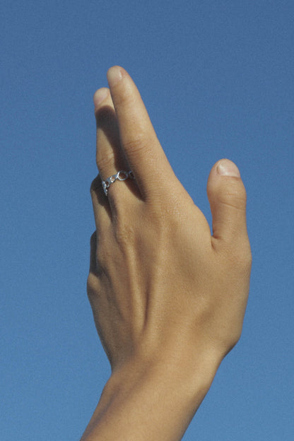 Hand with a ring on a clear blue sky background. Moneh Brisel Current Ring