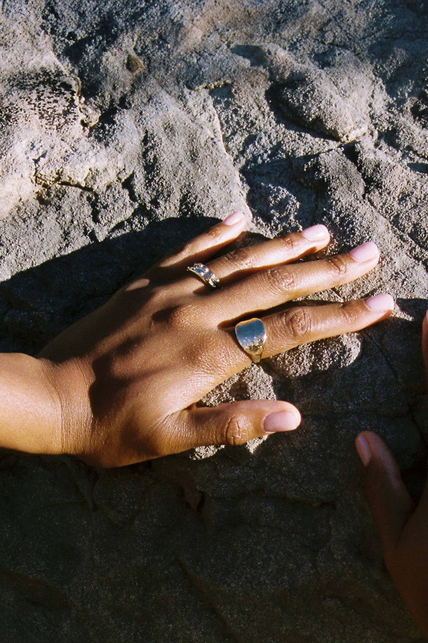 Hand with a ring on a textured surface. Moneh Brisel The Sun Ring