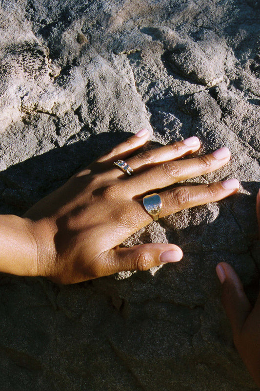 Hand with a ring on a textured surface. Moneh Brisel The Sun Ring
