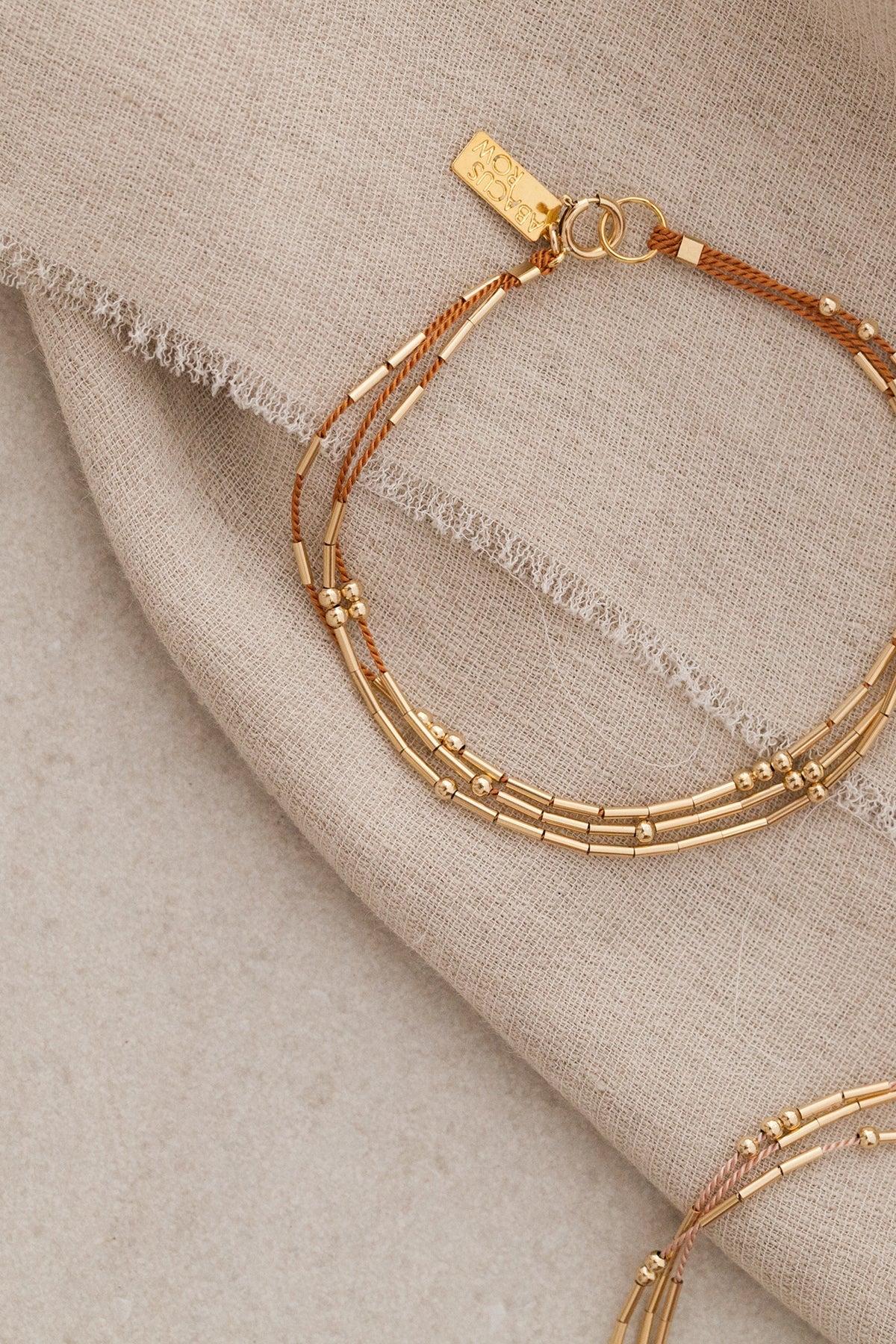 A refined and effortless bracelet designed to elevate your day-to-day. The Ara is a triple-stranded silk cord bracelet stacked with gold tubes and rounds that shift freely.