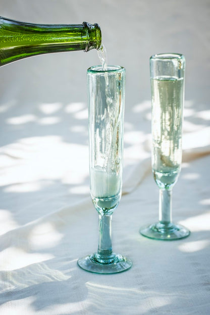 A playful champagne flute with a unique silhouette, designed to keep the party going. Each glass is handmade from recycled glass by artisan partners in Bogotá, Colombia, giving every piece its own subtle character.