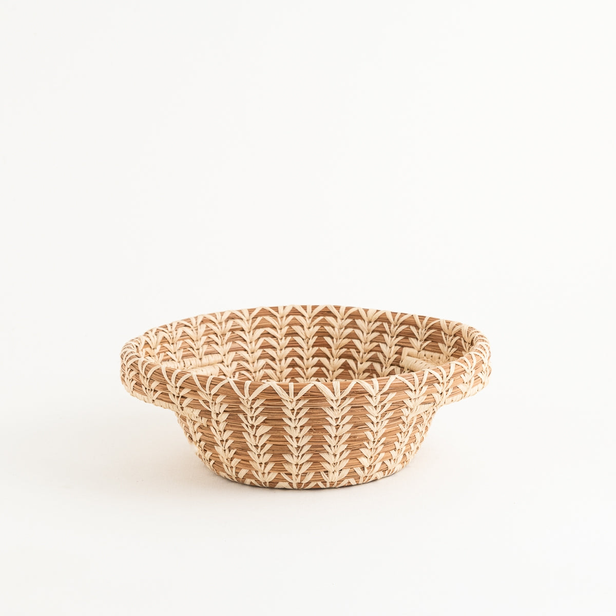 A pine needle basket with lacy handles was designed by Mayan Hands artisan partners. Basket lovers like to display its intricate raffia stitching, but this basket is functional and practical too.