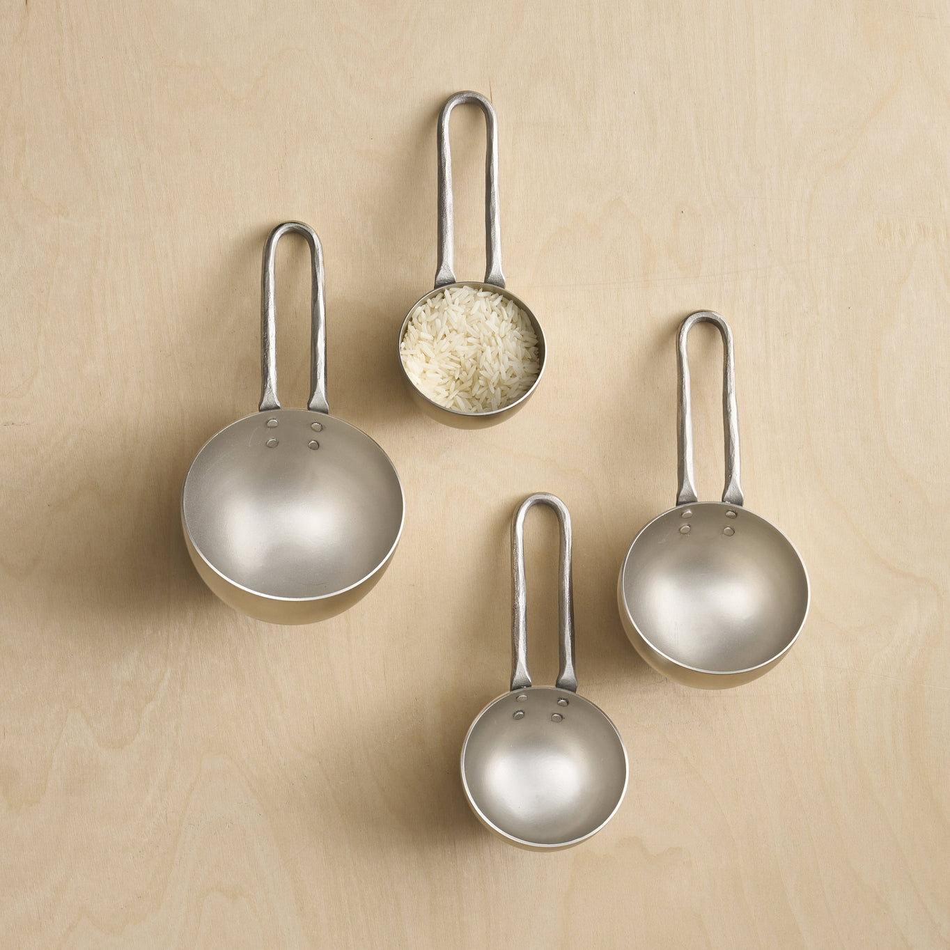 Deep, half-sphere scoops feature smooth, shiny exteriors and brushed interiors for an overall modern look of mixed textures and tones. Handles are forged of mild steel, giving them a hammered texture. Each scoop shows its capacity stamped on the side, from 1/4 cup up to 1 cup.