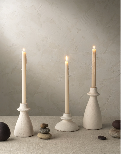 Handmade terracotta candlesticks lit against a neutral background