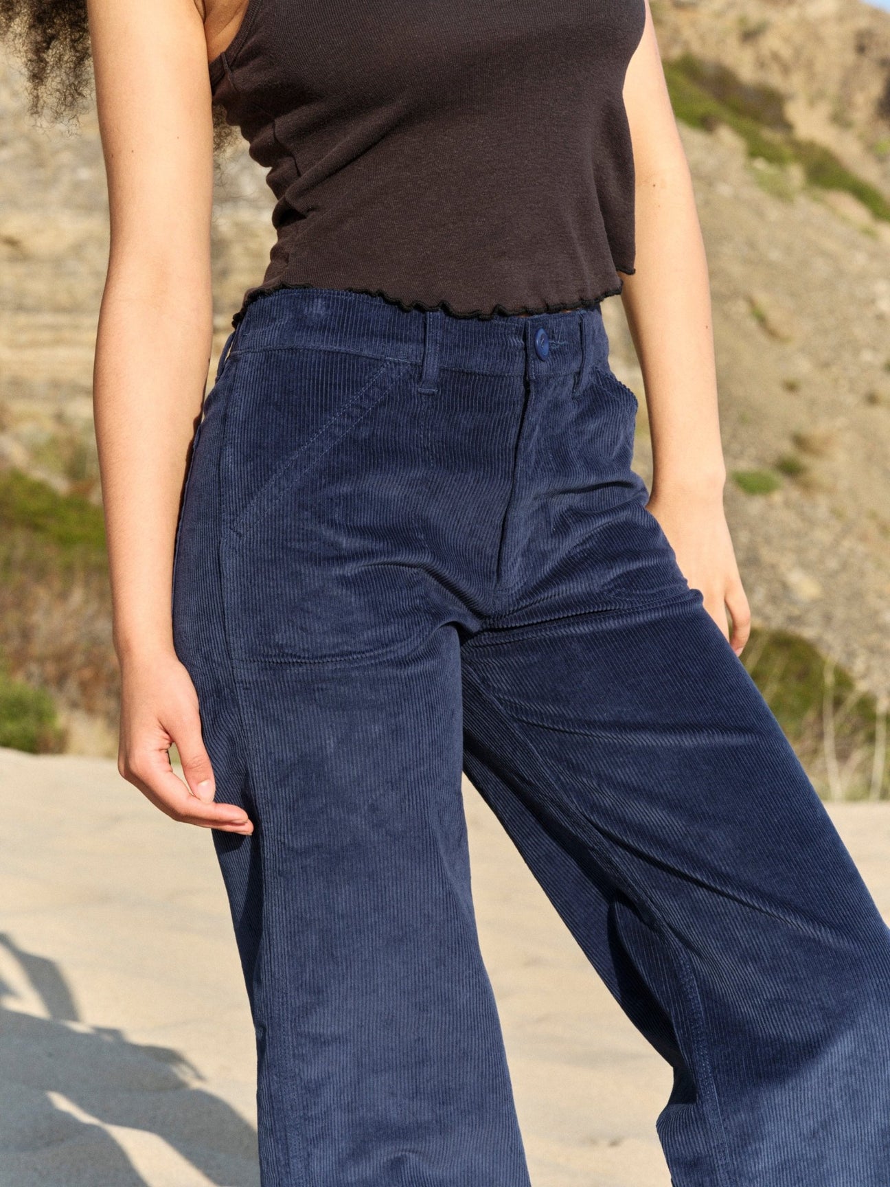 Person wearing blue corduroy pants and a black top outdoors. Mollusk Surf Shop Mid Rise Corduroy Painter Pants