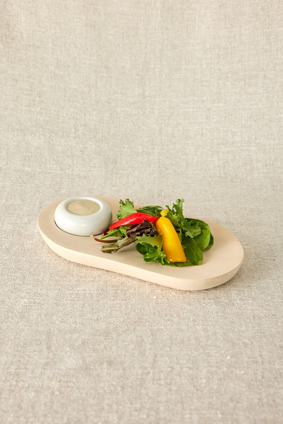 This wooden plate, thoughtfully shaped by hand, boasts organic edges for a unique touch and is accompanied by a pristine white ceramic bowl. With its rustic charm this versatile plate effortlessly doubles as a charming side dish or centerpiece. Handmade in South Africa.