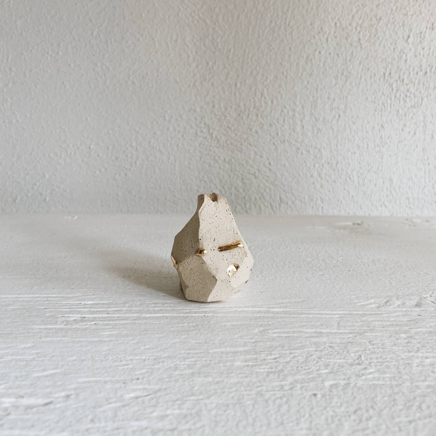 A small, hand-sculpted incense holder, carved and shaped into a small mountain shape.  Made from various types of clay, some that are mixed and marbled together and some that are highlighted with gold accents around the edges.
