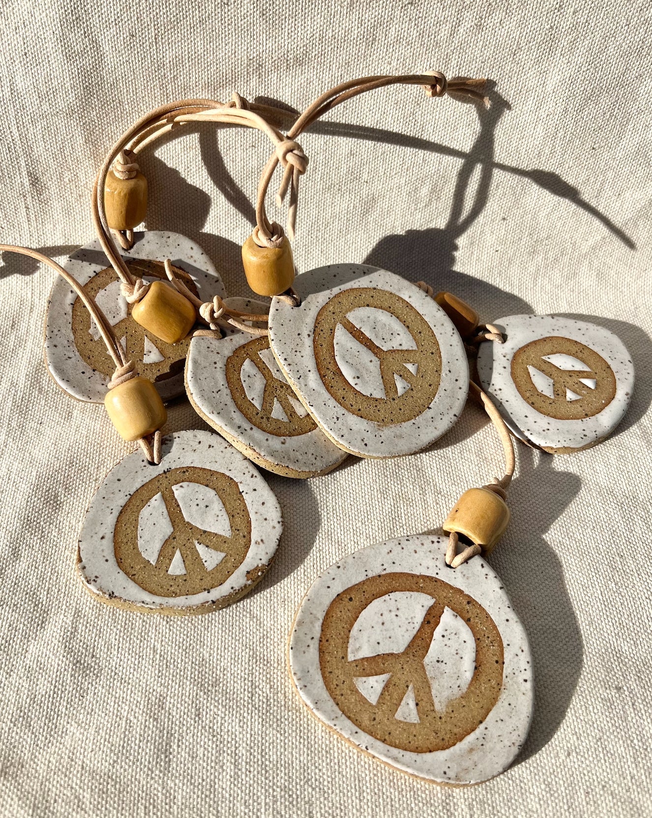 Add a hint of peace to your space with these peace offerings. Speckled clay peace signs adorned with a vintage wooden bead and leather cord. Hand built, glazed and fired in SLO, Ca.
