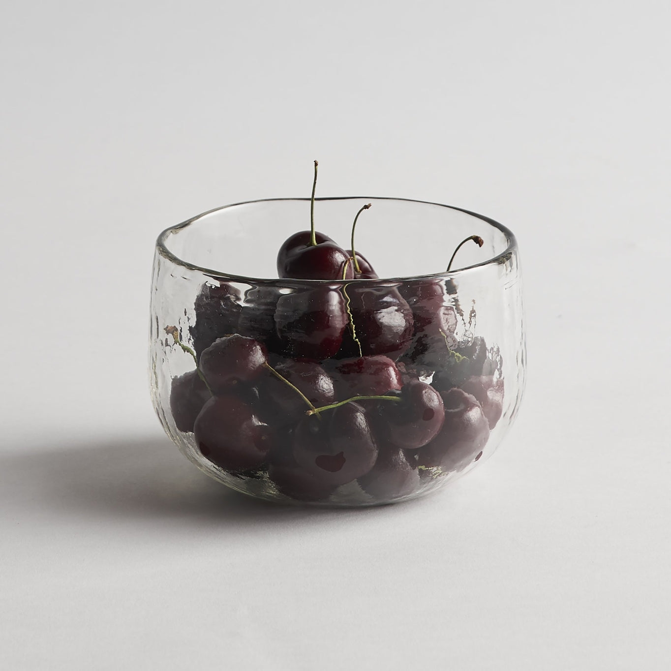 Clear, thick glass bowls are far from ordinary with their straight-sided shape and polished, dimpled exterior. These versatile bowls are nicely sized for a serving of soup or as a compact tabletop display piece. 
