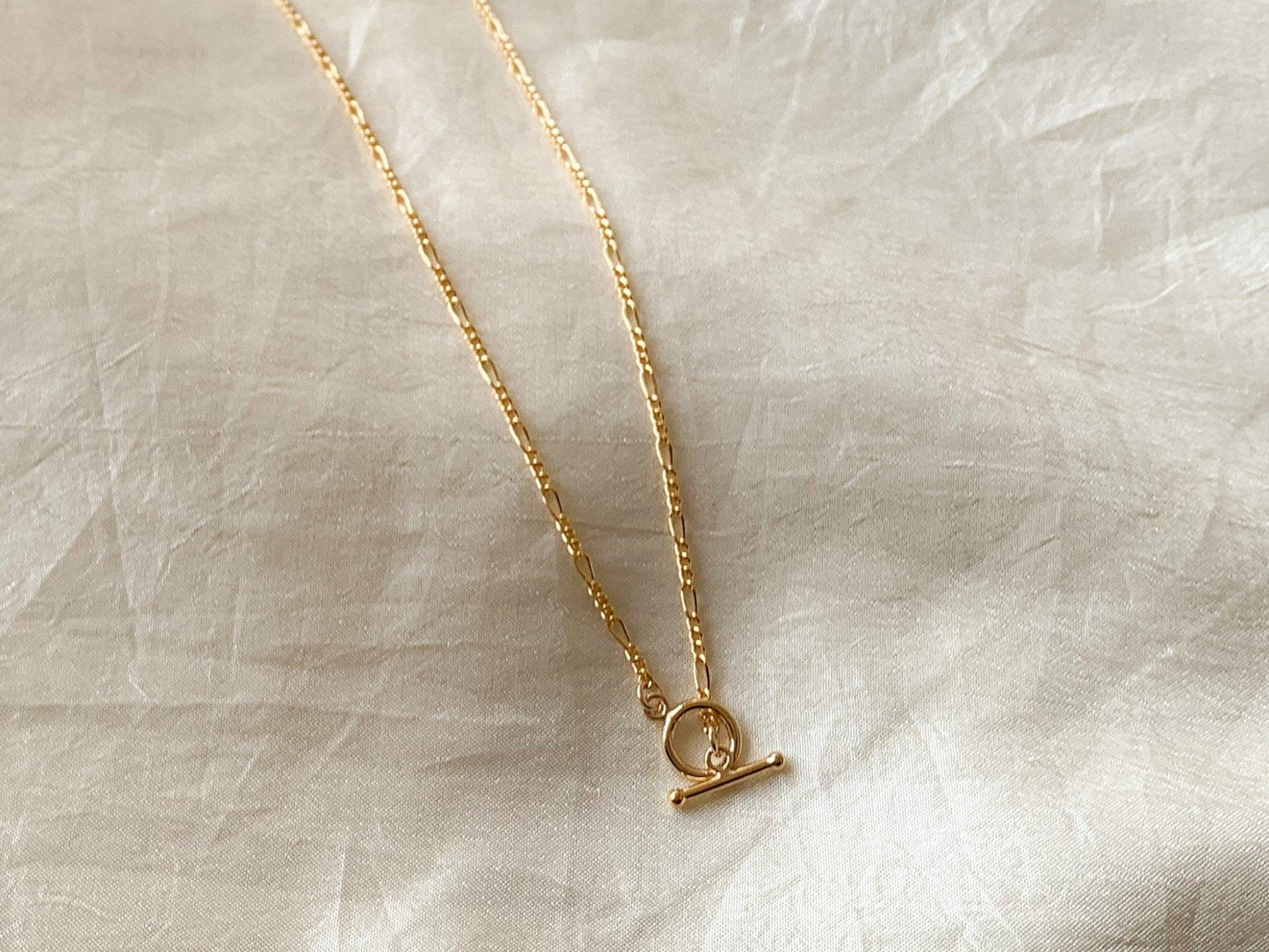 Dea dia / Dainty, lightweight 14k gold fill Figaro chain with toggle clasp closure. Wear it alone for a simple statement or layer it up for higher impact. Clasp can be worn in the front or back. 16.75" length - Designed and handmade in Los Angeles.