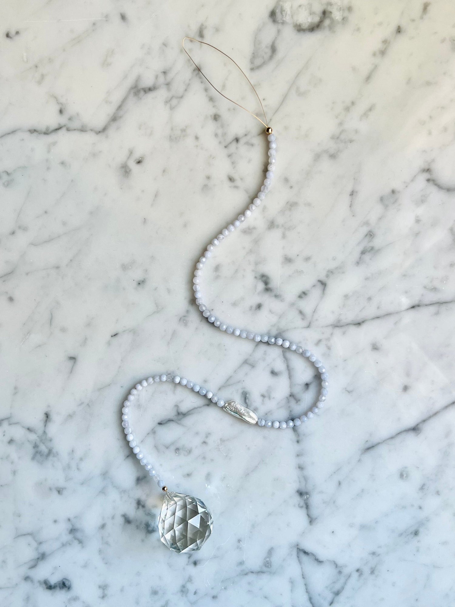 Adorn your space with a window prism - hang in a sunny spot & watch the rainbows dance!  In need of a little peace & quiet? Blue Lace Agate & Pearl pair washes away tense energies & pulls in tides of relief & tranquility.   Designed in California by Carrie Marill.