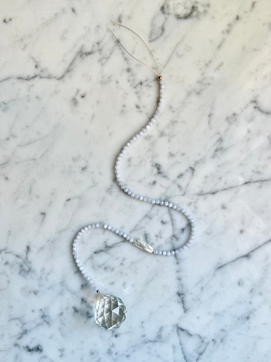 Adorn your space with a window prism - hang in a sunny spot & watch the rainbows dance!  In need of a little peace & quiet? Blue Lace Agate & Pearl pair washes away tense energies & pulls in tides of relief & tranquility.   Designed in California by Carrie Marill.