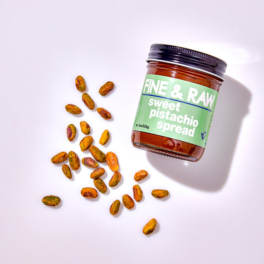 Jar of 'Fine & Raw' sweet pistachio spread with pistachios on a white background