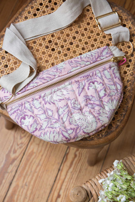 An adorable quilted cotton waist bag with an all-over floral print. Features a plain adjustable strap and golden zipper fastening. Made with 100% organic cotton.