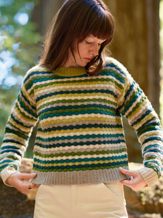 Woman wearing a striped sweater in a forest setting. Mollusk Surf Shop Kilim Sweater