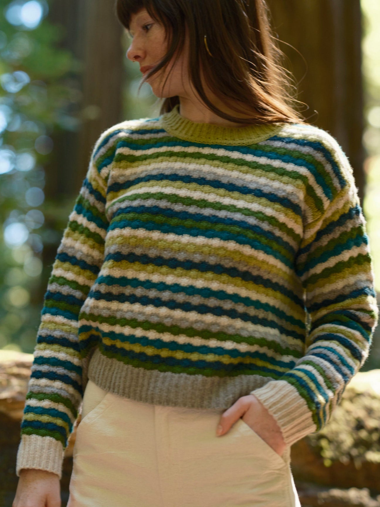 Person wearing a striped sweater in a forest setting. Mollusk Surf Shop Kilim Sweater