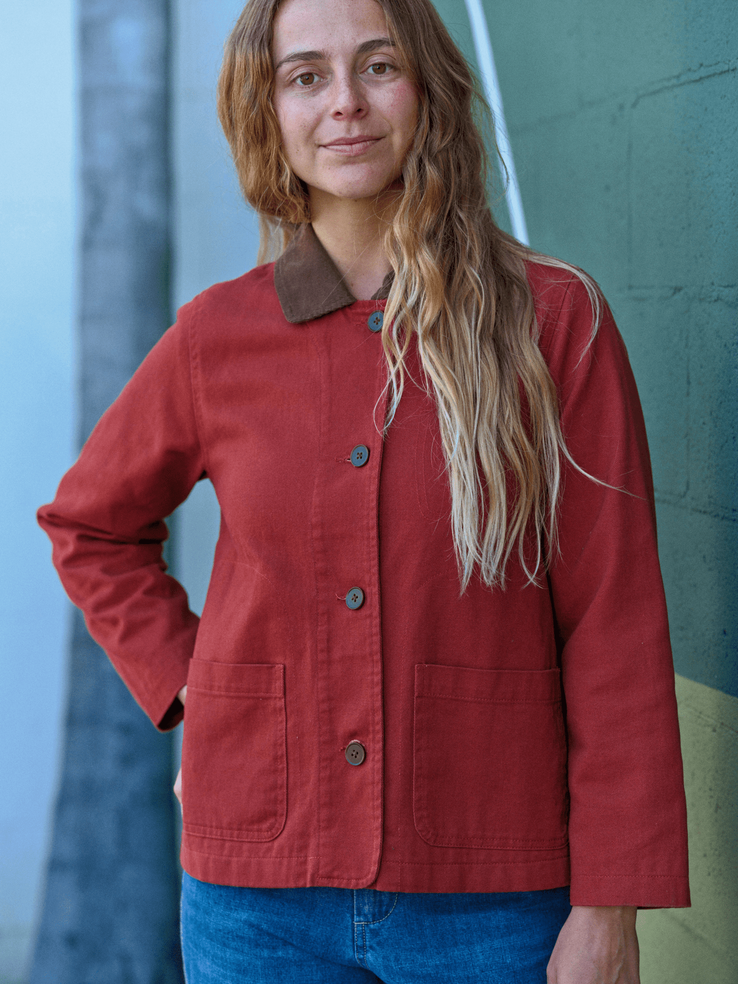 Woman wearing a red jacket with a brown collar against a textured wall. Mollusk Surf Shop Lined Painter Jacket 
