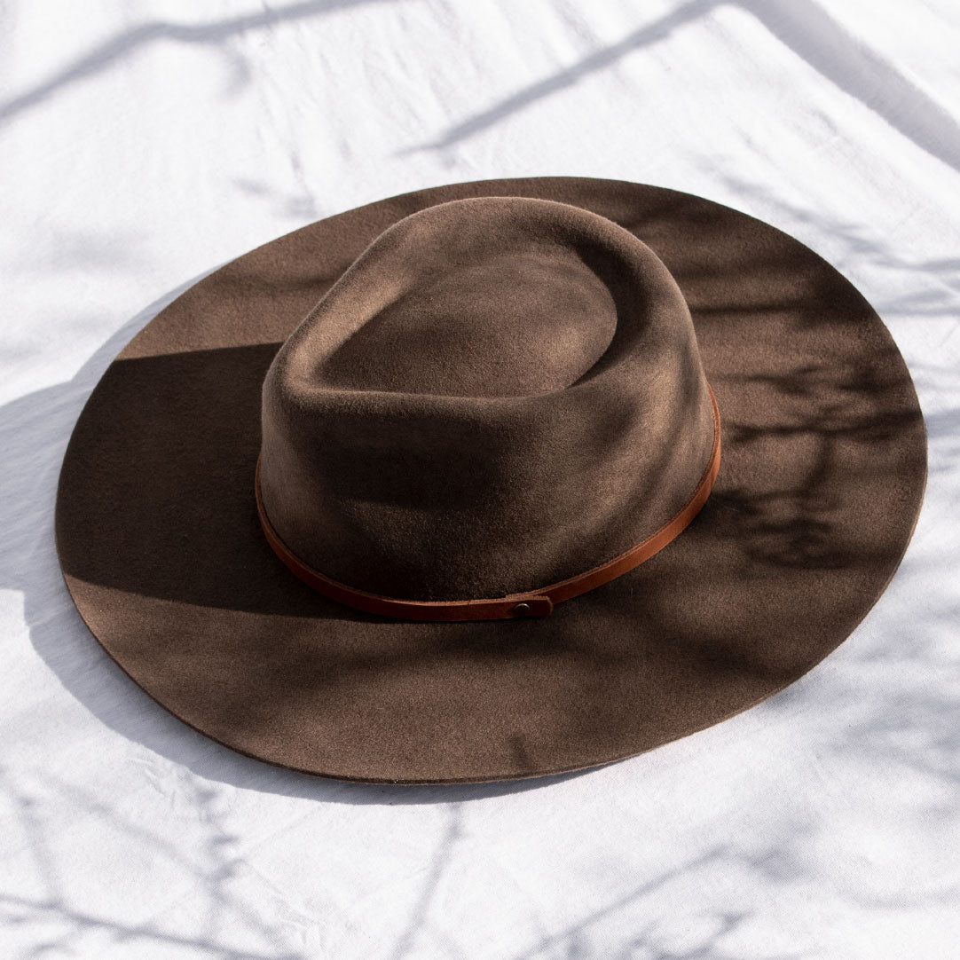 Minga's classic Rancher hat design, handmade from sheep's wool, is the perfect touch of sophistication. Wide-brimmed with a teardrop crown, and finished with a vegetable-tanned leather tie. Crafted with natural fibers makes for a versatile, all-season hat.