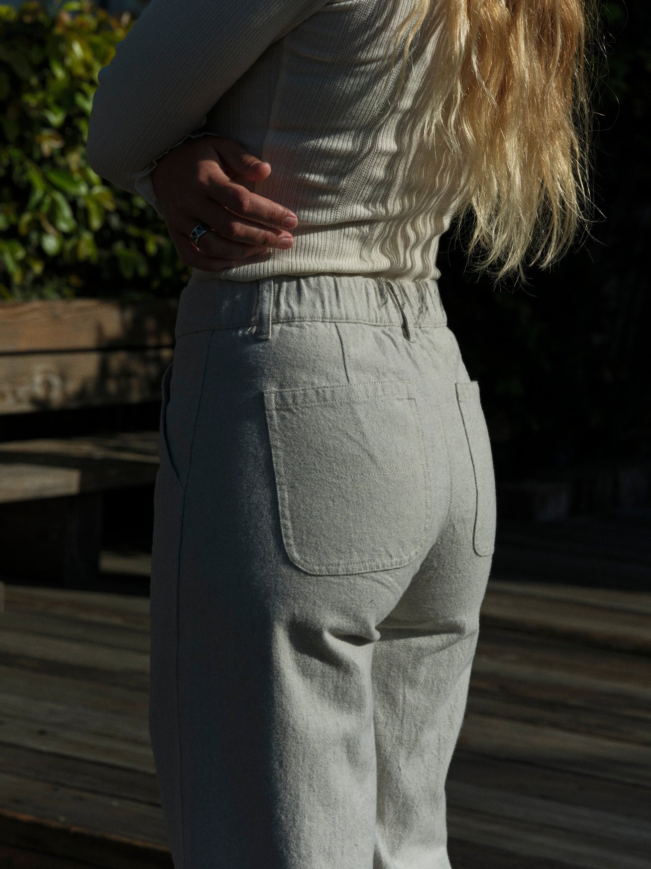 Person wearing a beige sweater and light gray pants in a garden setting. Mollusk Surf Shop Mid Rise Painter Pants 
