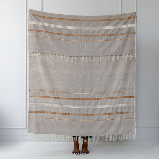 This handmade, eco friendly, Fair Trade throw blanket is beautiful and versatile. The design is a traditional Ethiopian motif. The cotton is hand spun and the throw is woven on one of the large looms in the Sabahar workshop. This throw blanket is finished with Sabahar's signature twisted fringes.
