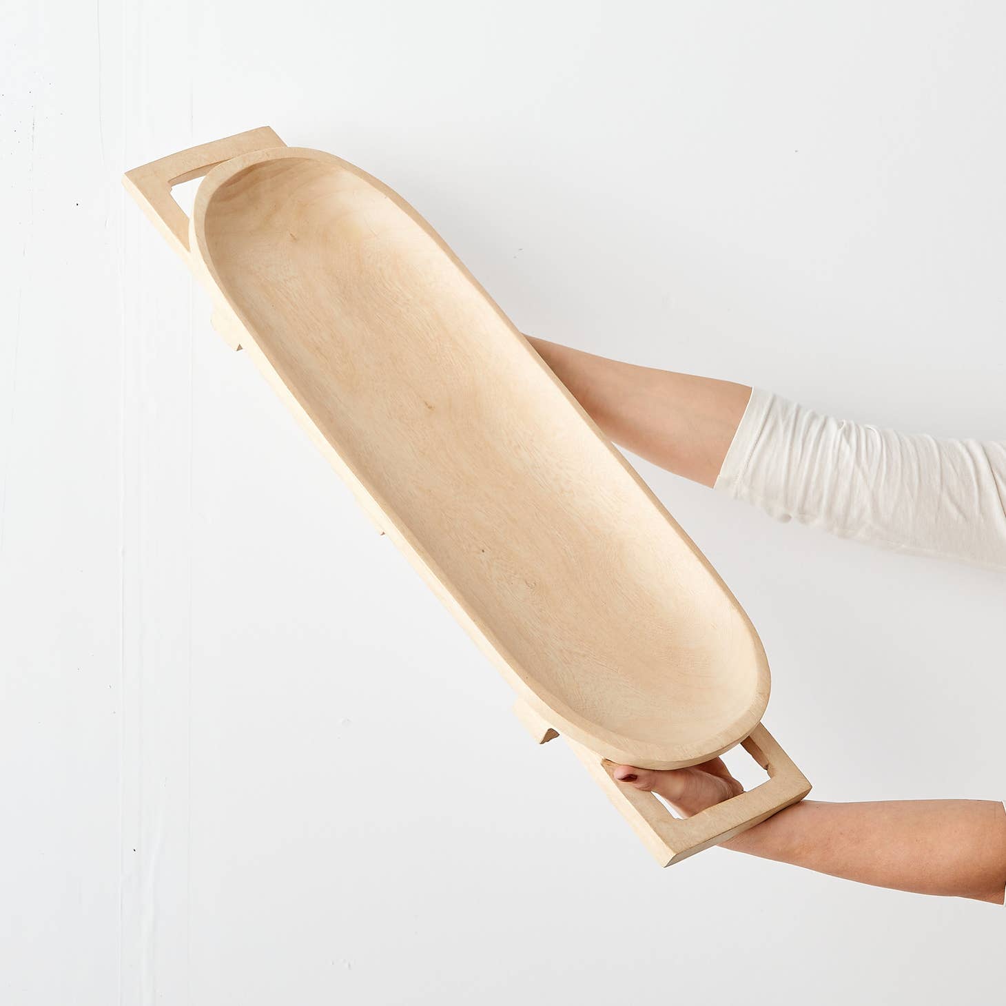 These elegant, raised long trays are hand carved in Eswatini from sustainably sourced Jacaranda wood, a form of rosewood that is very common throughout southeast Africa. They are carved from a single piece of wood, including the legs and handles, and polished to a natural sheen, available in a raw, light wood finish.