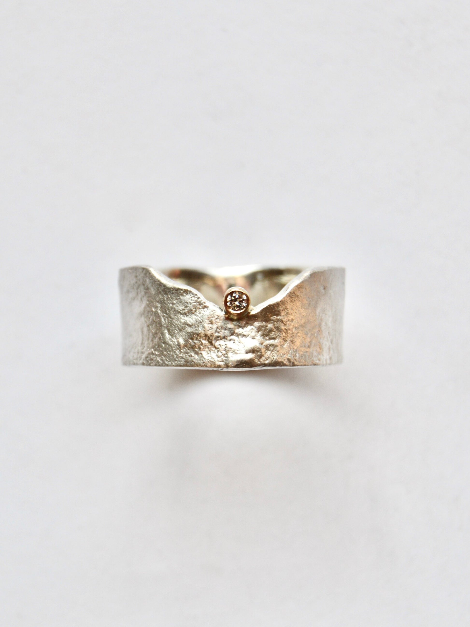 Made by hand in Northern New Mexico using recycled metals and responsibly sourced stones, this timeless, heirloom piece is sure to make a statement.  This ring features a Sterling Silver reticulated band with a recycled white diamond set in 14kt yellow gold.