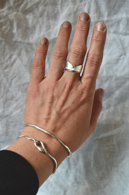 Made by hand in Northern New Mexico using recycled metals and responsibly sourced stones, this timeless, heirloom piece is sure to make a statement.  This ring features a Sterling Silver reticulated band with a recycled white diamond set in 14kt yellow gold.