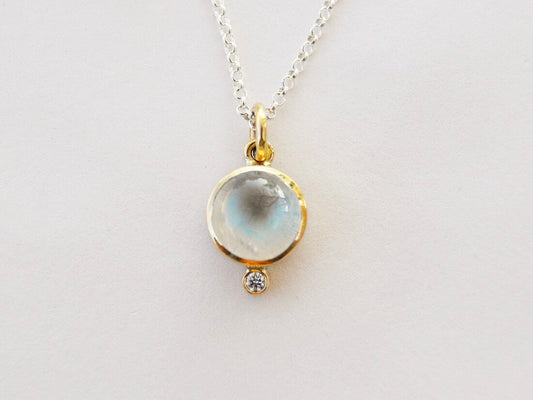 Made by hand in Northern New Mexico using recycled metals and responsibly sourced stones, this timeless, heirloom piece is sure to make a statement.    Polished moonstone sits next to a white diamond, held 14kt yellow gold with an 18" sterling silver rolo chain.