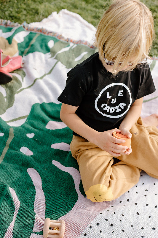 A fun little organic kids tee with a super cute little Leucadia smiley face by local artist Zach Smith. Printed on an organic cotton, fair trade tee with all proceeds to San Diego area families facing housing insecurity. Keep it funky, keep it kind, keep it local.