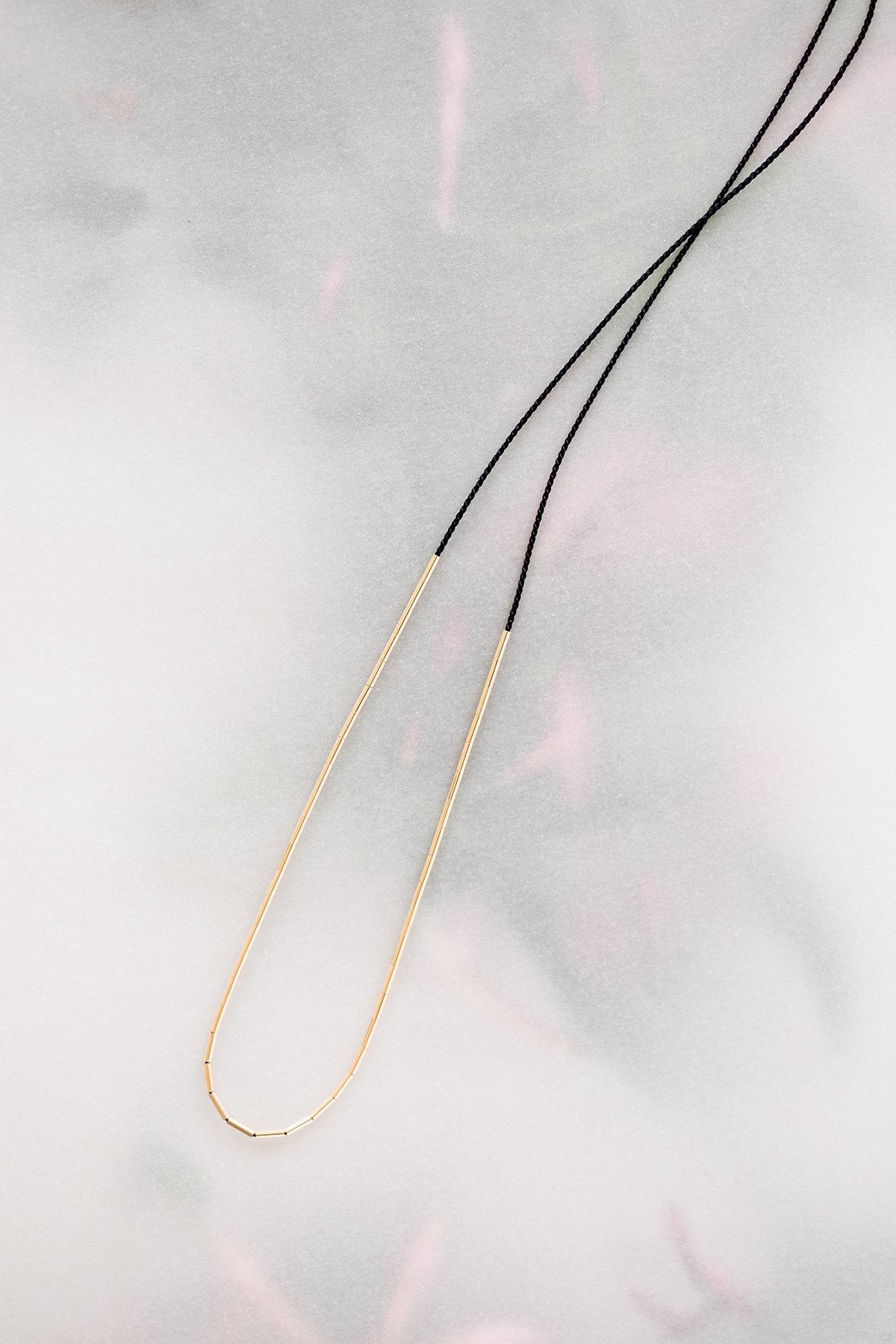 The Dorado Necklace by Abacus Row - long black silk cord necklace with 14k gold fill tubes that can be moved around on the cord to create multiple minimalist looks
