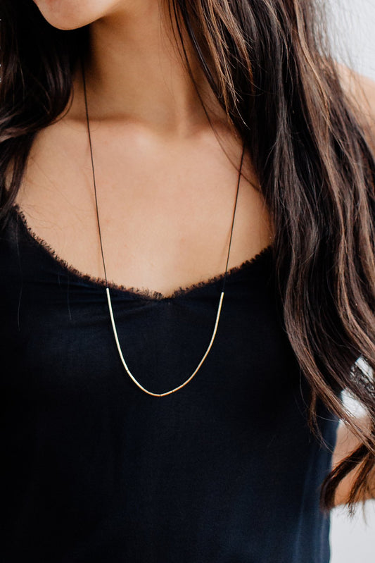 The Dorado Necklace by Abacus Row - long black silk cord necklace with 14k gold fill tubes that can be moved around on the cord to create multiple minimalist looks