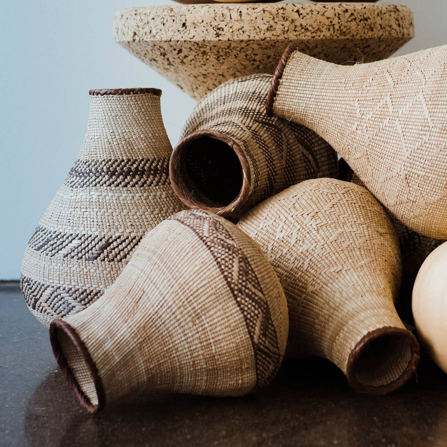 Handwoven by artisans in Africa to resemble the gourds traditionally used for grain storage or water carrying, these baskets provide a delightfully natural  element, with varied abstract, geometric patterns created by weaving in darker fibers. 