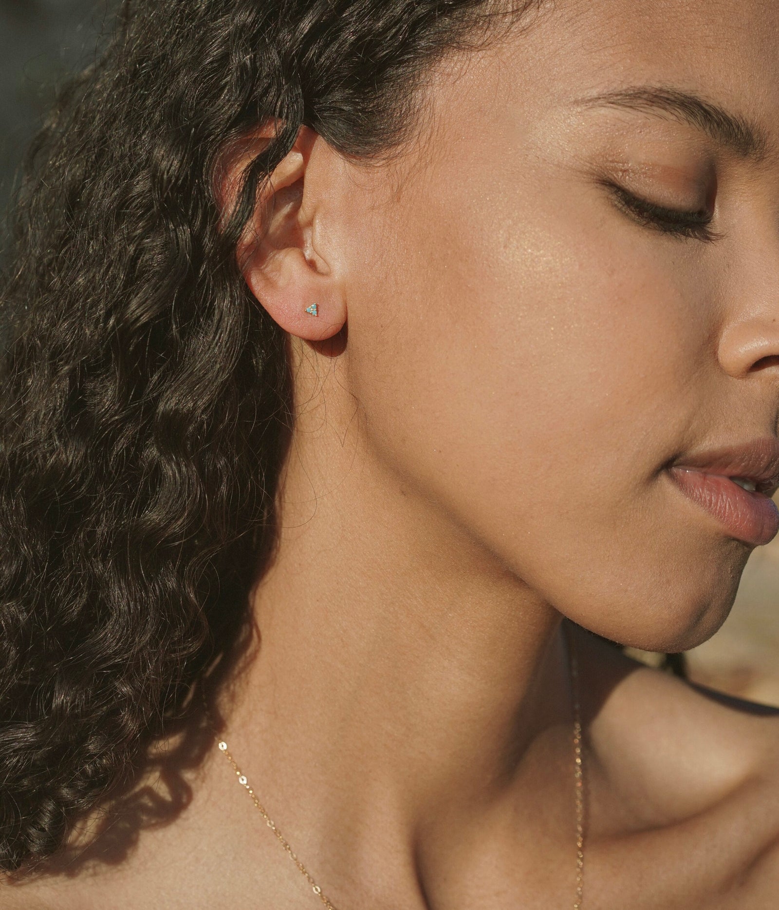 A tiny delicate triangular stud earring with triple prong set turquoise stones. Handmade in the Santa Cruz Mountains.