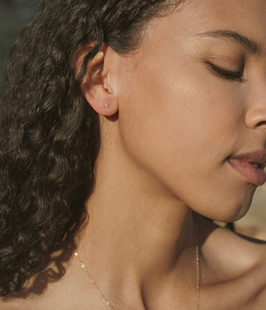 A tiny delicate triangular stud earring with triple prong set turquoise stones. Handmade in the Santa Cruz Mountains.