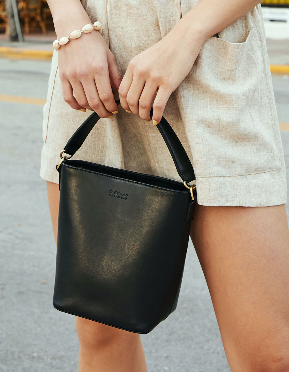 This classy bucket bag has one roomy interior and a slip-in pocket to grab your small essentials in a sec. Designed with a flat bottom, Bobbi stands on her own, making a true statement. Carry her with the top handle or wear her as a cross body bag. Made in India.