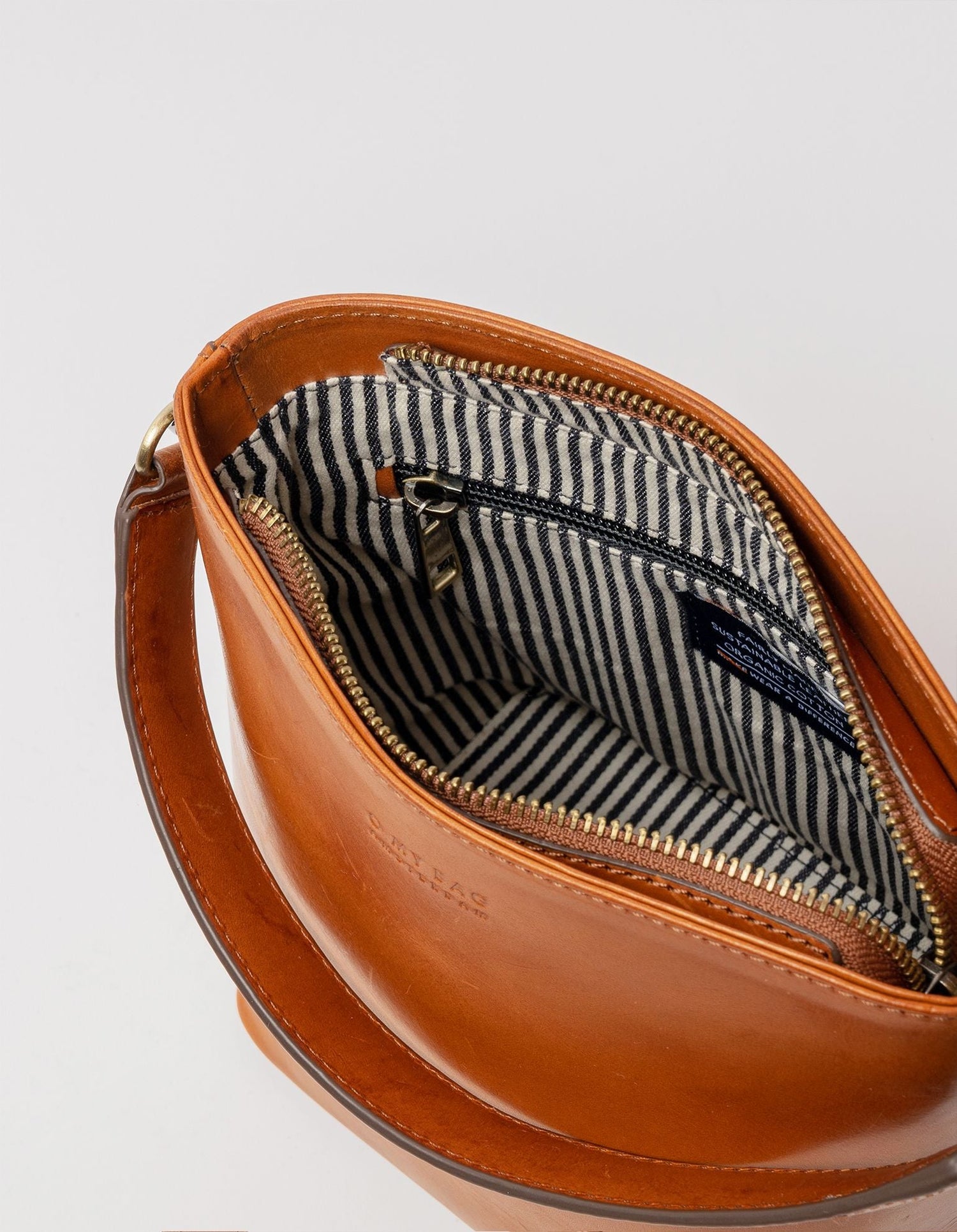 This classy bucket bag has one roomy interior and a slip-in pocket to grab your small essentials in a sec. Designed with a flat bottom, Bobbi stands on her own, making a true statement. Carry her with the top handle or wear her as a cross body bag. Made in India.