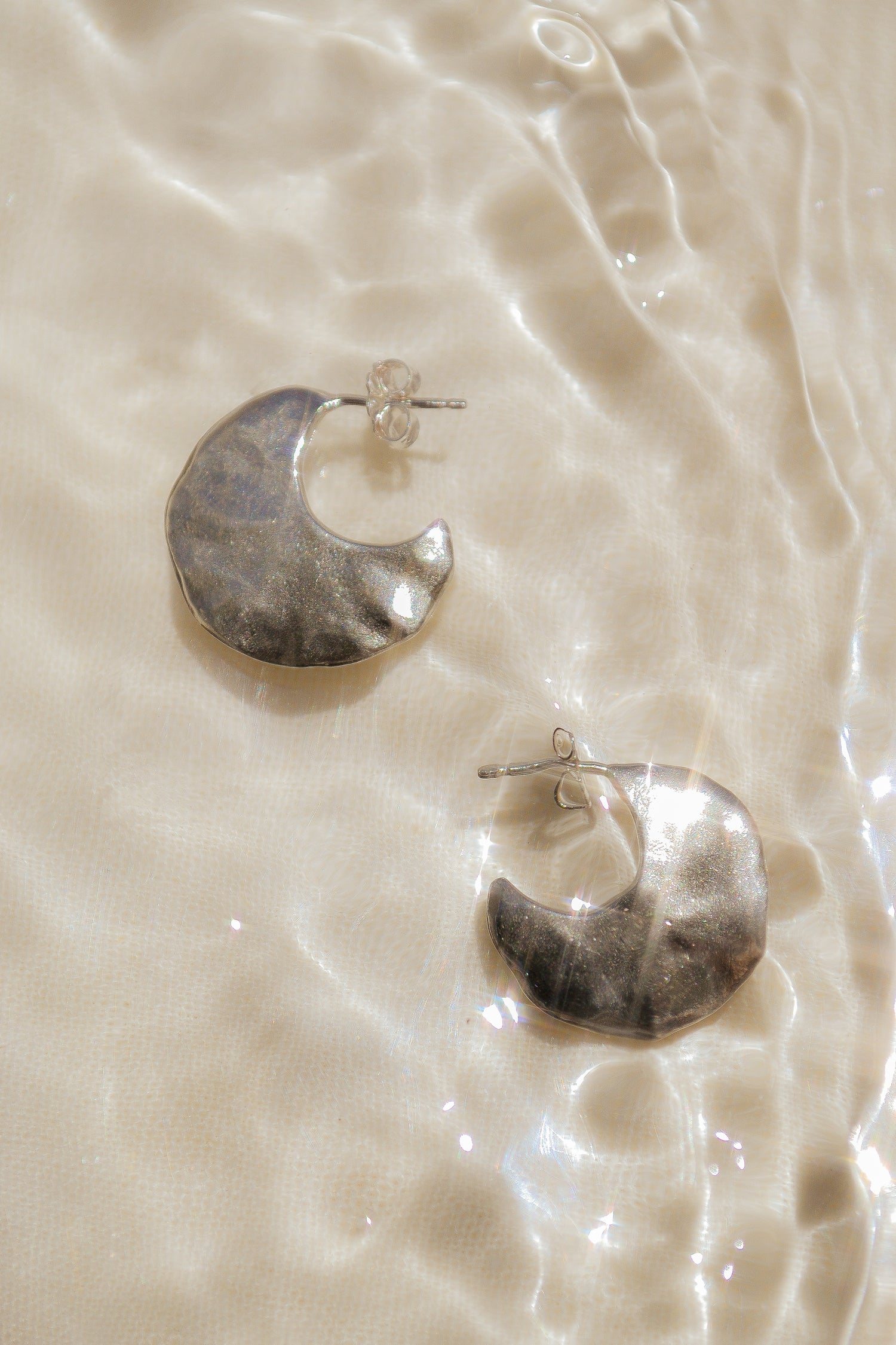 Bora Hoops by Amanda Hunt. A smooth yet slightly textured hoop. Light as a feather. Available in hand cast sterling silver with sterling silver posts or hand cast yellow bronze.
