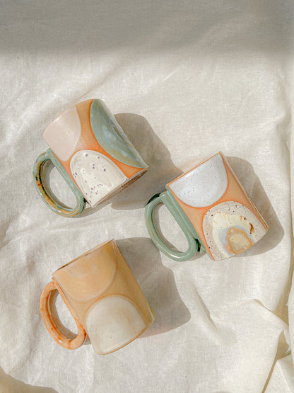 Handmade ceramic mug featuring unique glaze colors and a looped handle.