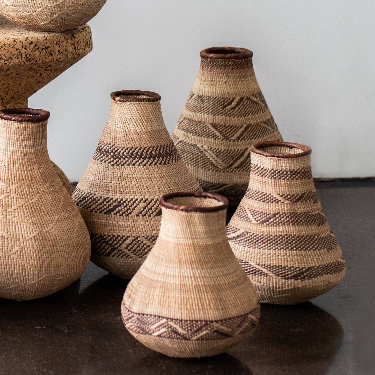 Handwoven by artisans in Africa to resemble the gourds traditionally used for grain storage or water carrying, these baskets provide a delightfully natural  element, with varied abstract, geometric patterns created by weaving in darker fibers. 